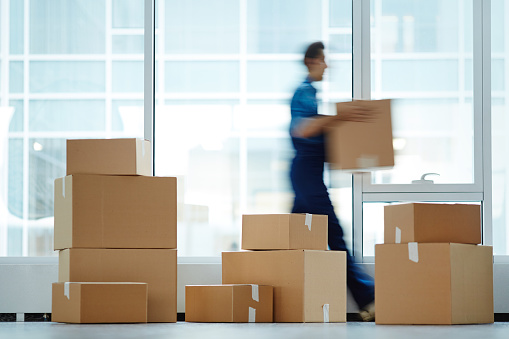 A blurred man moving boxes in a new office