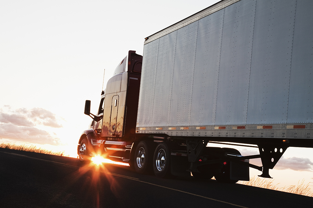 A commercial moving truck with a sunset behind it